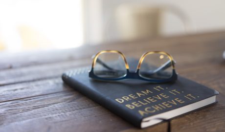 journal on wood table with glasses on top